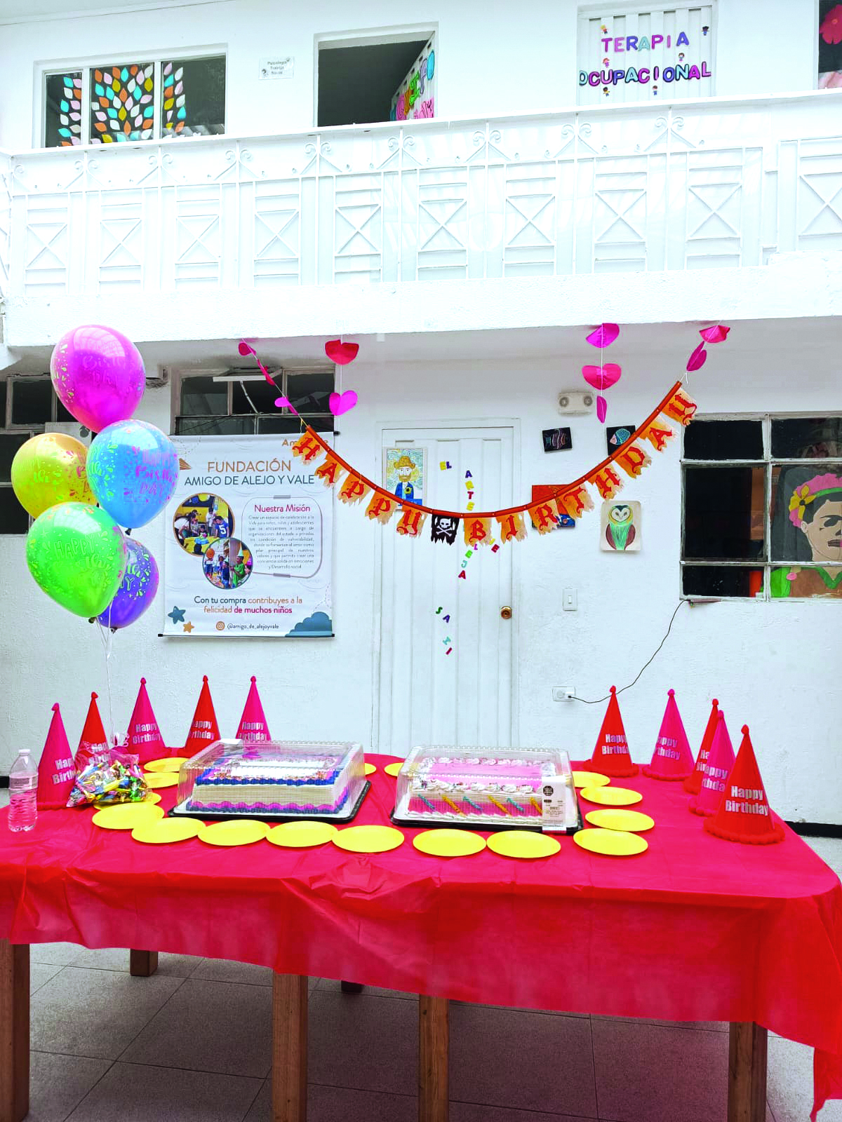 Mesa decorada con globos, torta y regalos para niños